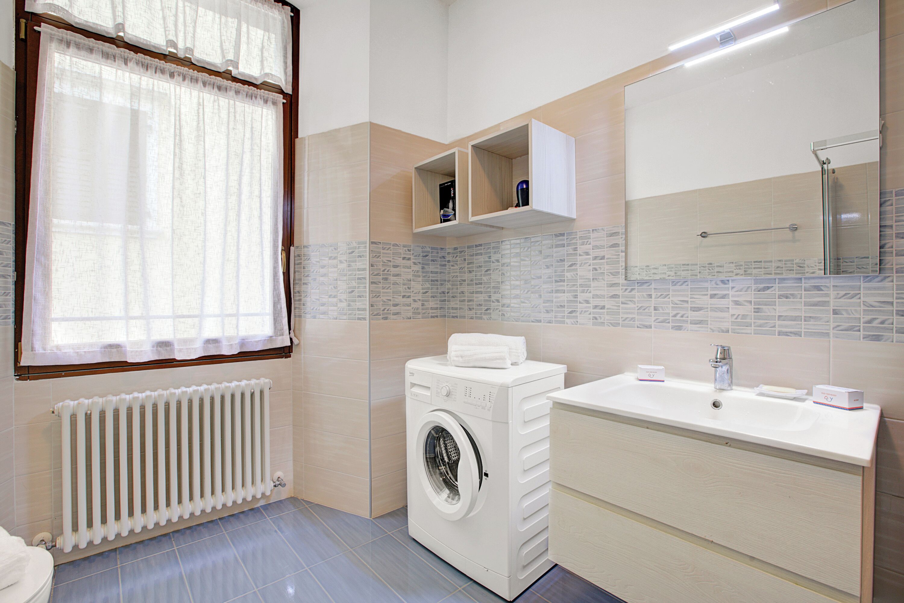 A modern bathroom with a built-in washing machine, a sink, and a mirror.