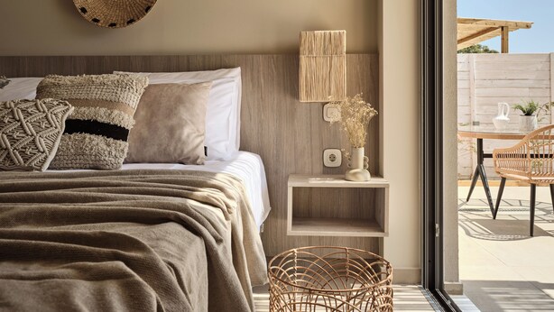 Une chambre à coucher avec un lit, une table de chevet, une lampe et une vue sur l’extérieur.