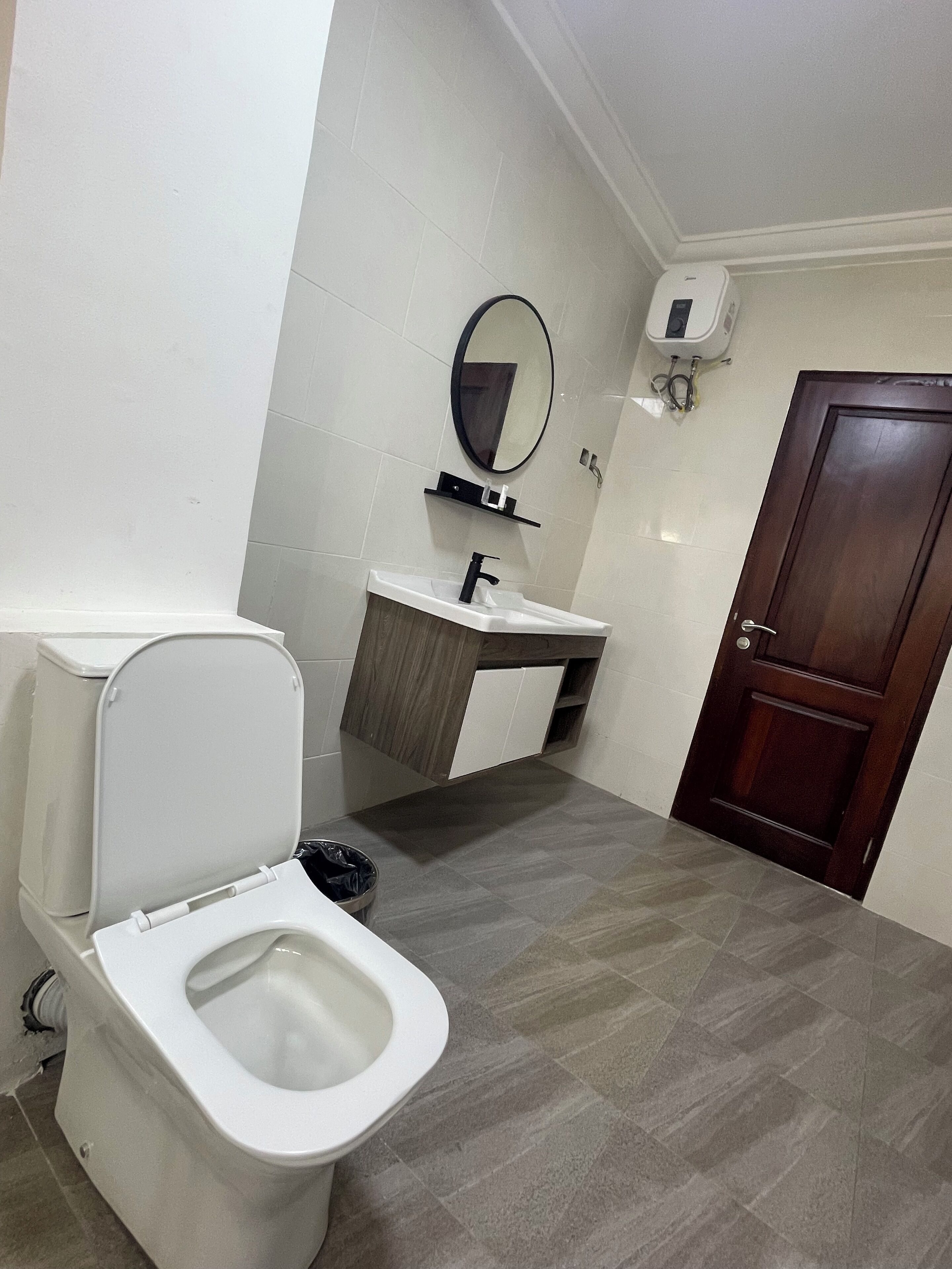 Un baño con inodoro, bidé, lavamanos, espejo y puerta de madera.