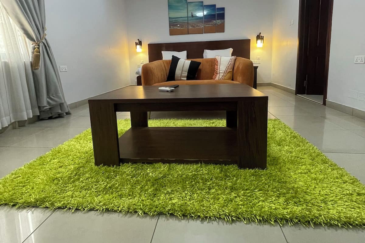 A modern bedroom with a bed, a coffee table, and a painting on the wall.