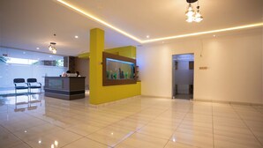 A modern hotel lobby with a reception desk, chairs, a fish tank, and a clean, tiled floor. - Aklin Hotel and Resorts (Accra)