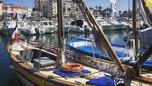 A marina with boats docked, a prominent building with a dome in the background, and a clear blue sky. - Charming seafront studio with terrace and pools in private residence (Saint-Raphaël)