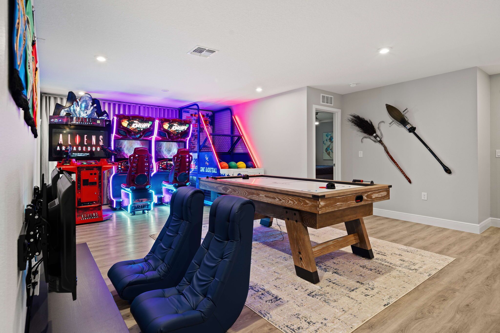 Quarto com mesa de bilhar, área de jogos com máquinas de fliperama e suporte para tacos.