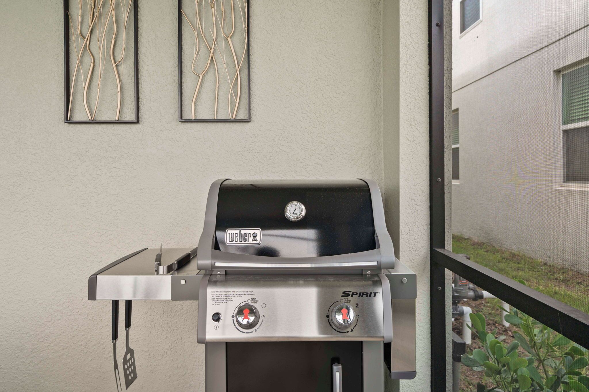 Un barbecue à gaz Weber Spirit doté de deux boutons de contrôle, d’un thermomètre numérique et d’une table d’appoint en acier inoxydable.