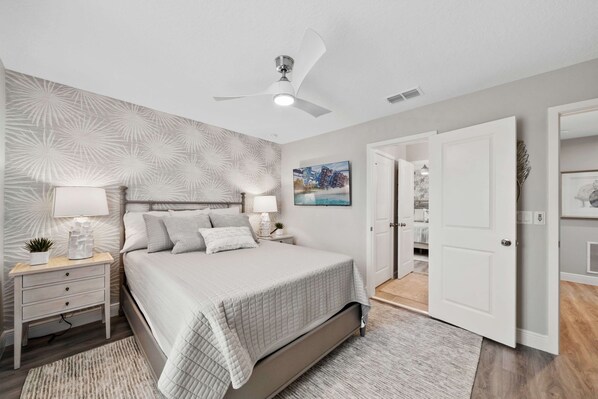 A bedroom with a bed, nightstands, a ceiling fan, and a door leading to another room. - 9127 Turquoise Wave Cove (Kissimmee)