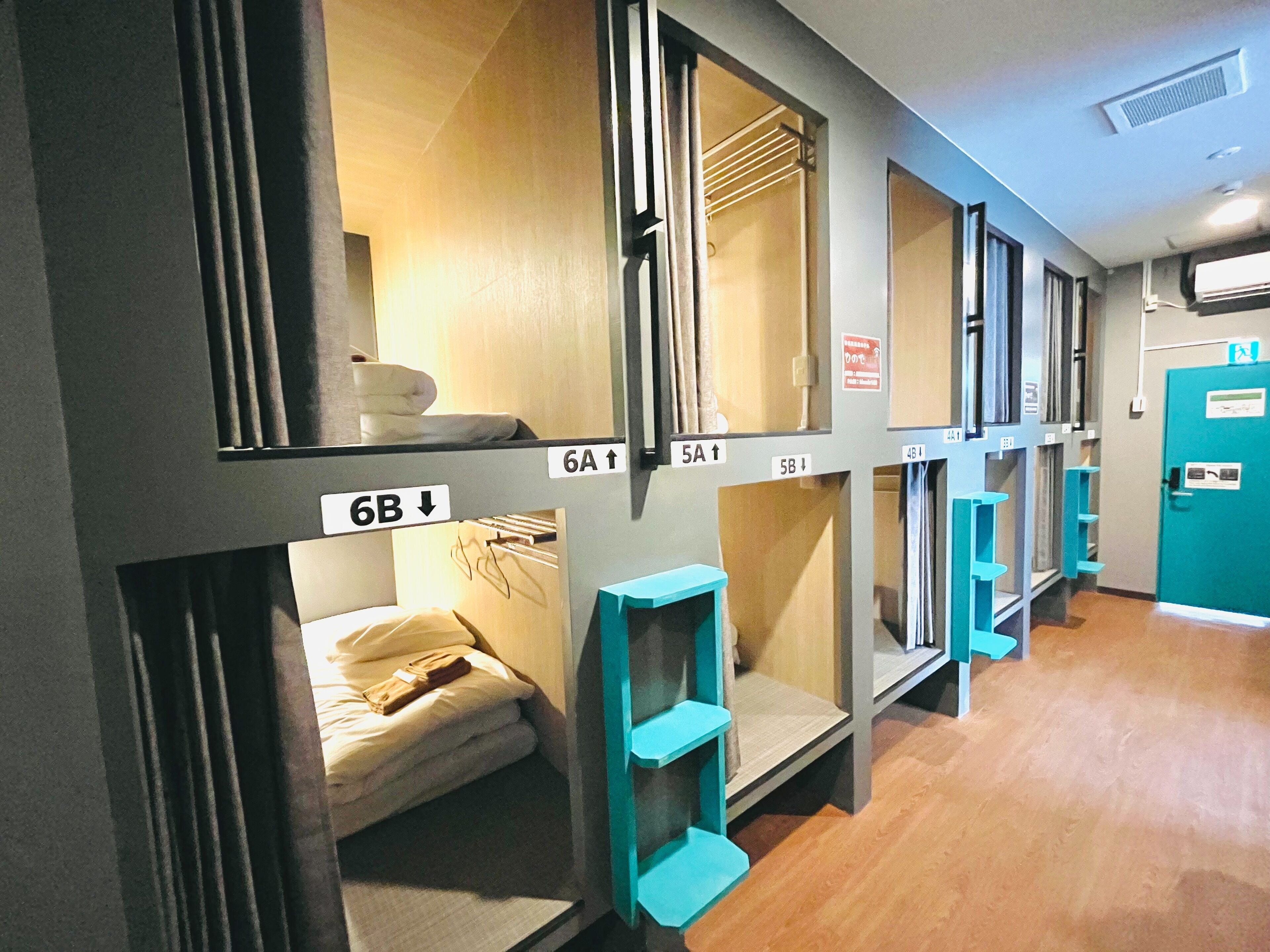 Une chambre d’hôtel avec des lits superposés, un petit bureau et une étagère bleue.