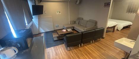 Kompakti hotellihuone, jossa on pieni keittiönurkkaus, sohva, sänky ja pieni kylpyhuone.