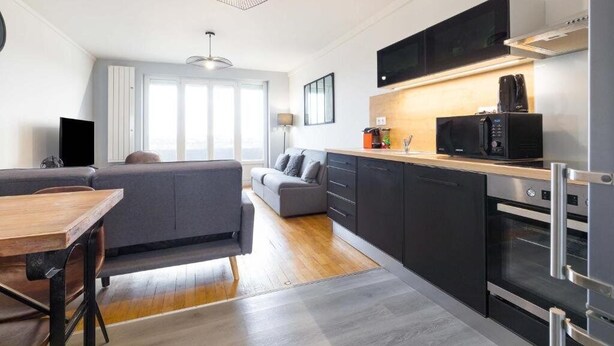 A compact kitchen with a microwave, oven, and modern pendant light.