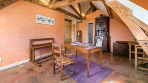 A rustic room with exposed wooden beams, a wooden table with chairs, a vintage radio, and a fireplace. - Le Panoramique - Exceptional View (Dijon)