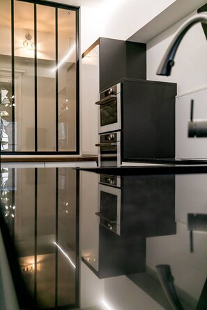 Enjoy cooking in this well-equipped kitchen with an oven, range hood, and modern faucet.