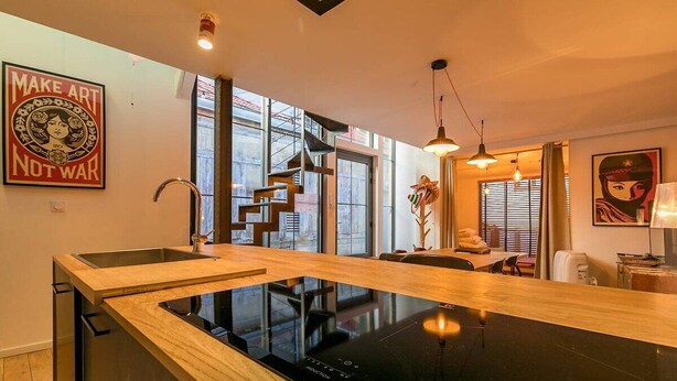 Une cuisine moderne dotée d’un plan de travail en bois, d’une cuisinière intégrée et offrant une vue sur la ville grâce à de grandes fenêtres.