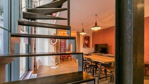 Un intérieur moderne avec un escalier en colimaçon, un coin repas et une grande fenêtre.