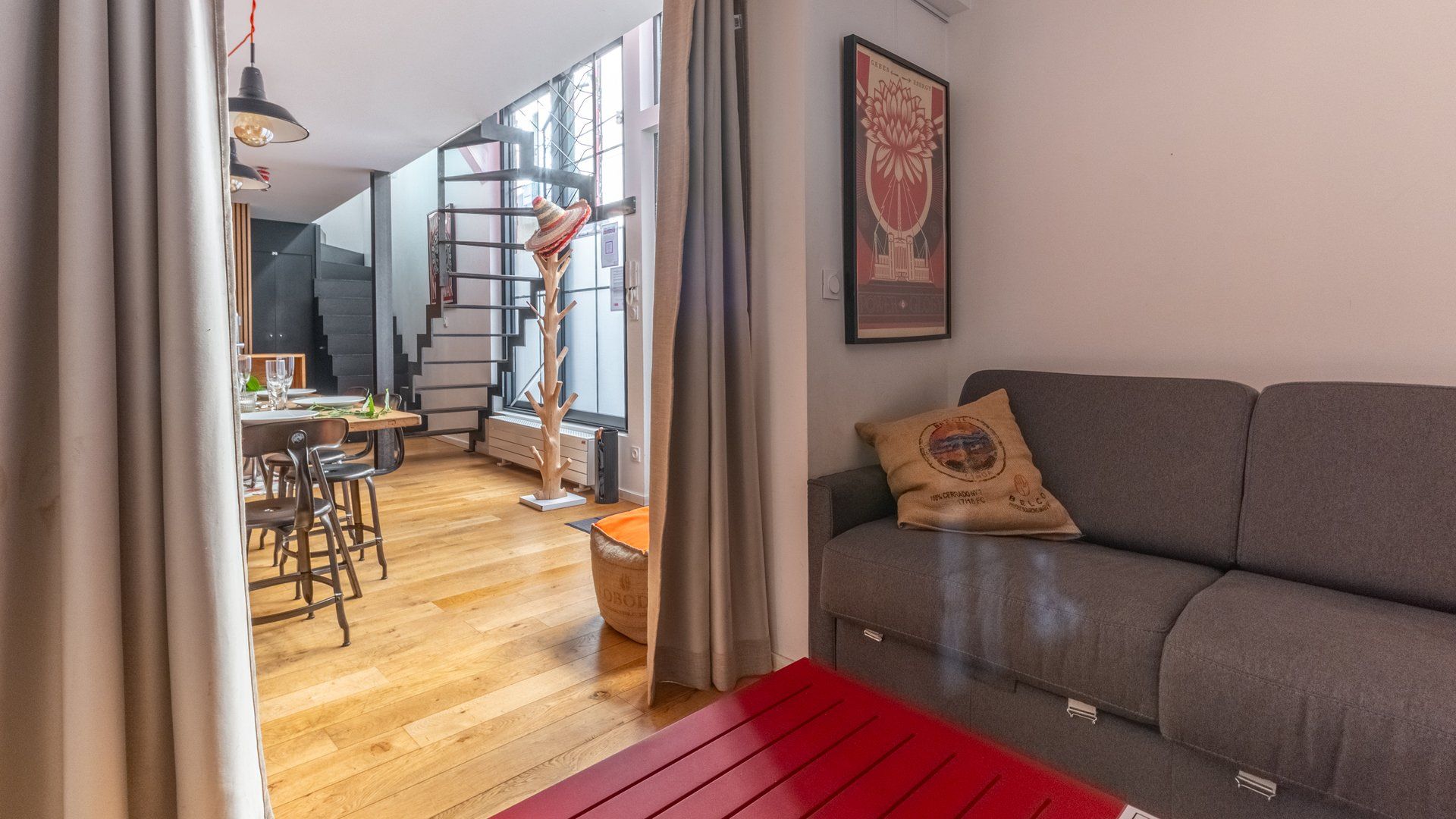 Un espacio de estar moderno con sofá, zona de comedor y escalera.