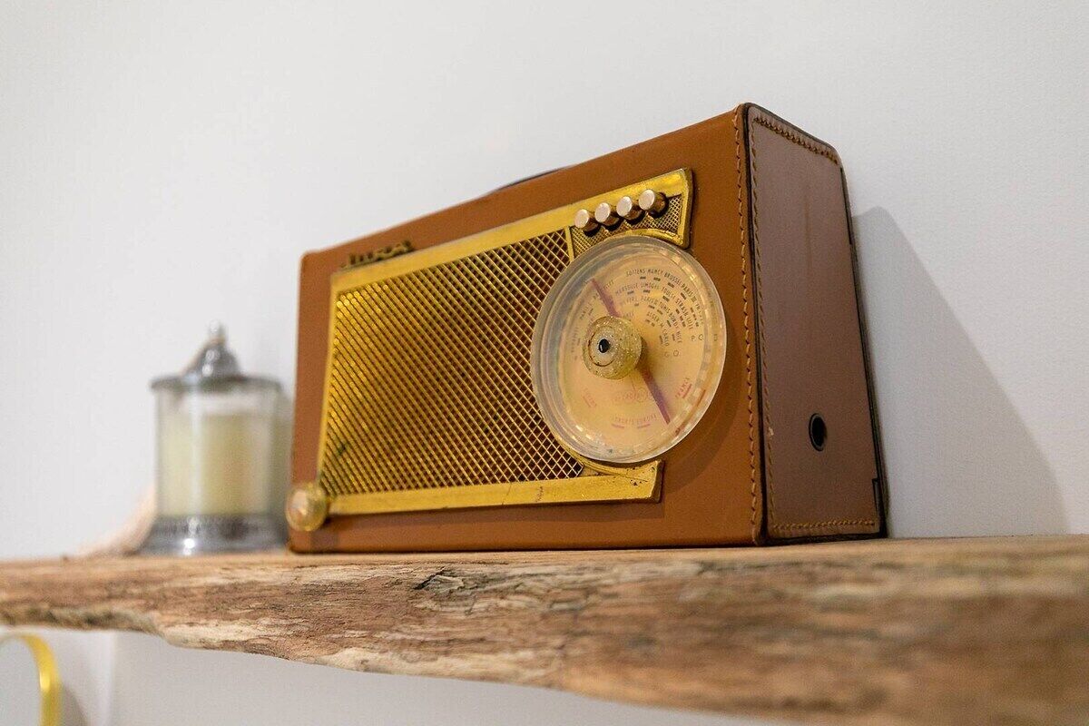 Une vieille radio posée sur une étagère en bois.