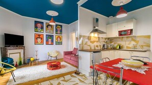 Una sala de estar moderna con una mesa de comedor roja, una cocina con un microondas rojo y un techo con patrones geométricos.