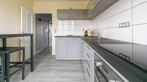 Una cocina moderna con gabinetes grises, encimera de acero inoxidable y horno empotrado.