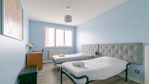Un dormitorio con dos camas, un aparador, un radiador y una ventana.