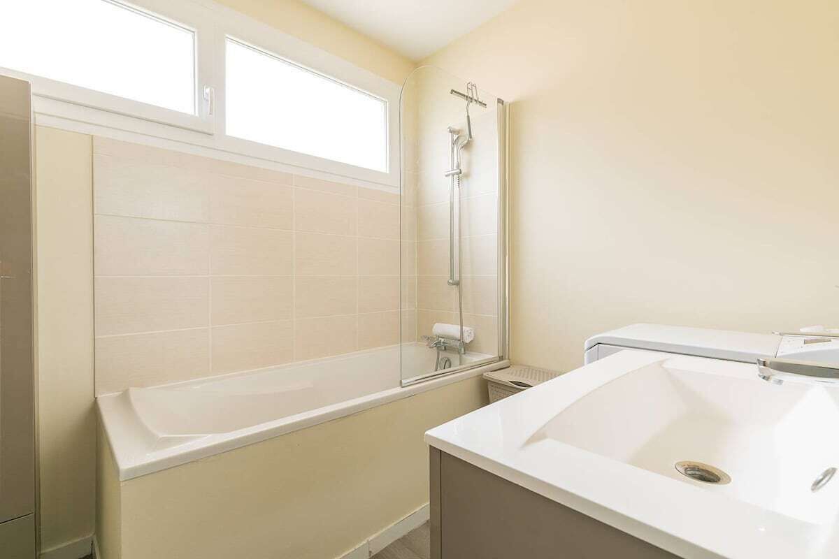 Een badkamer met een bad, douche, wastafel en raam.
