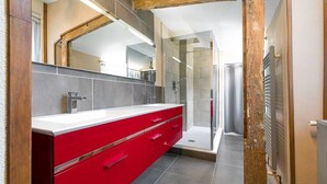 Une salle de bain moderne avec un meuble-lavabo rouge, une cabine de douche en verre et un grand miroir.