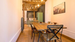 Un coin repas avec une table et des chaises en bois, un réfrigérateur vert et un panneau indiquant l’emplacement d’un bar.