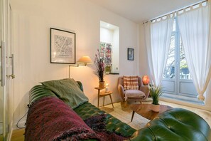 A living room with a green sofa, a chair, a lamp, and a window with curtains. - le Tillot (Dijon)