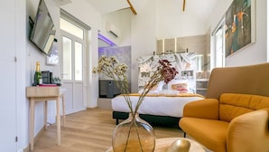 Ett modernt hotellrum med en säng, en soffa, en tv och en vas med blommor.
