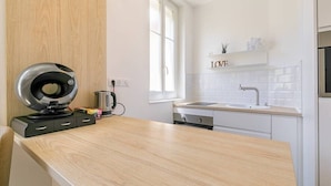 Eine moderne Küche mit einer Holzausziehtheke, einem Wasserkocher, einer Kaffeemaschine und einem Fenster.