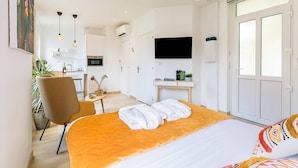 Ett modernt hotellrum med en säng, ett skrivbord, en stol, en TV och ett stort fönster.