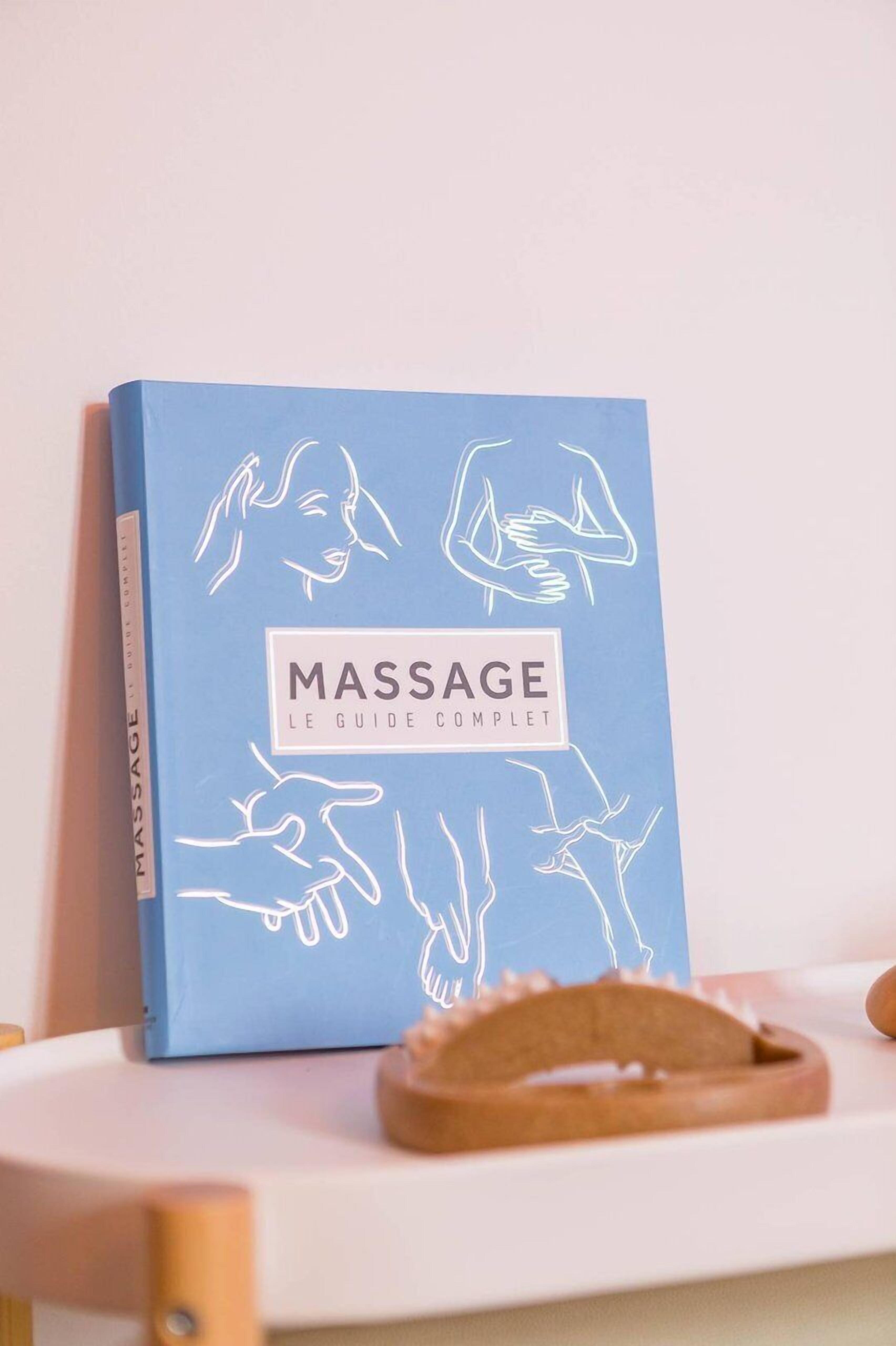 A blue book titled 'MASSAGE' with white line drawings of massage techniques on a white surface.