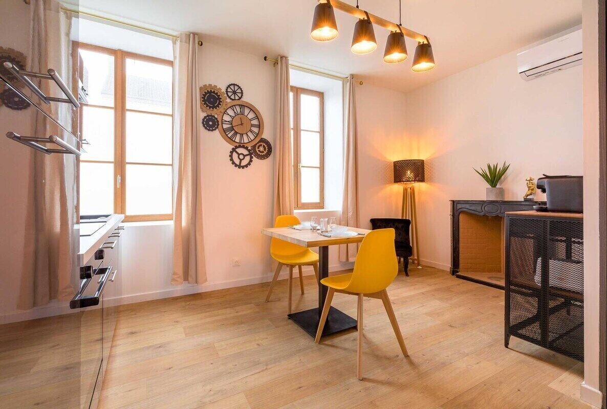 A modern kitchen with a dining table, chairs, and a hanging light fixture.