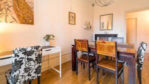 Un comedor con una mesa y sillas de madera, una consola blanca y un lámpara colgante, además de un cuadro en la pared.