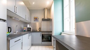 Una cocina moderna con gabinetes grises, campana extractora de acero inoxidable, horno empotrado y ventana que proporciona luz natural.