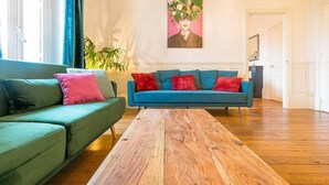 Una sala de estar con un sofá verde, un sofá azul y una mesa de centro de madera.