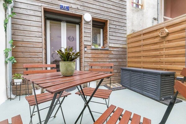A wooden building with a patio area featuring a table and benches, a small window, and a wooden fence. - Château Biek (Dijon)