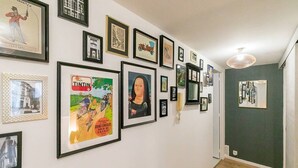 A hallway with framed artwork on the walls, a mirror, and a light fixture. - Château Biek (Dijon)