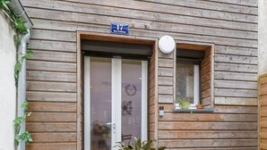 A wooden exterior wall with a door, a small window, and a sign above the door. - Château Biek (Dijon)