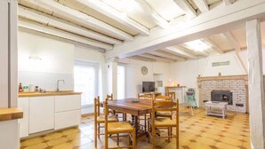 A spacious kitchen with a wooden dining table and chairs, a white countertop, and a brick fireplace. - La Cabotte d'Ahuy – Village House (Ahuy)