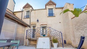 A courtyard with a table and chairs, a small garden, and a building with a balcony. - La Cabotte d'Ahuy – Village House (Ahuy)