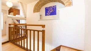 A staircase with wooden railings, a stone archway, and a blue artwork on the wall. - La Cabotte d'Ahuy – Village House (Ahuy)