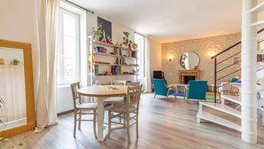 Una sala de estar con una mesa de comedor, sillas, una estantería, chimenea y una escalera de caracol.