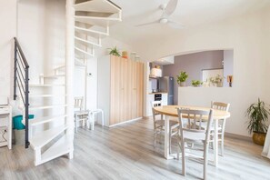 Een modern interieur met een wenteltrap, een eethoek met een houten tafel en stoelen, en een keuken met apparatuur en planten.