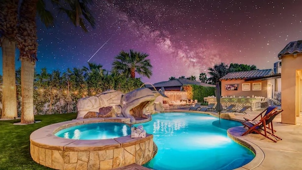 Ein Swimmingpool mit Whirlpool, umgeben von einer Steinterrasse und Palmen.