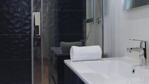 A modern bathroom with a glass shower enclosure, a white sink, and a towel on the counter. - La Chouette –  Cité Gastronomique (Dijon)