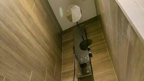 En duschhörna med modern design, utrustad med ett väggmonterat duschmunstycke och ett handhållet duschmunstycke.