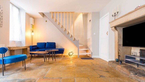 A living room with a blue sofa, a coffee table, a fireplace, and a staircase. - Le Duplex des Ducs- Au cœur du centre Historique- (Dijon)