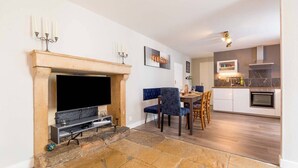 A living room with a fireplace, a television, and a dining area with chairs and a table. - Le Duplex des Ducs- Au cœur du centre Historique- (Dijon)