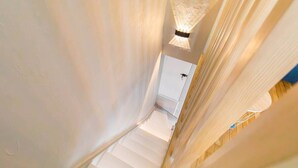 A narrow staircase with white walls and a door at the top. - Le Duplex des Ducs- Au cœur du centre Historique- (Dijon)