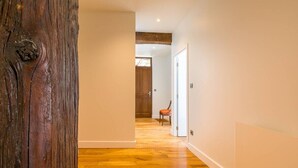 Un pasillo con suelo de madera, paredes blancas y una puerta de madera.