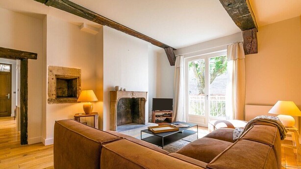 Una sala de estar con chimenea, sofá, televisor y una ventana con cortinas.