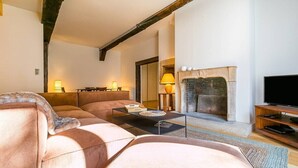 Una sala de estar con sofá, mesa de centro, chimenea y televisor.